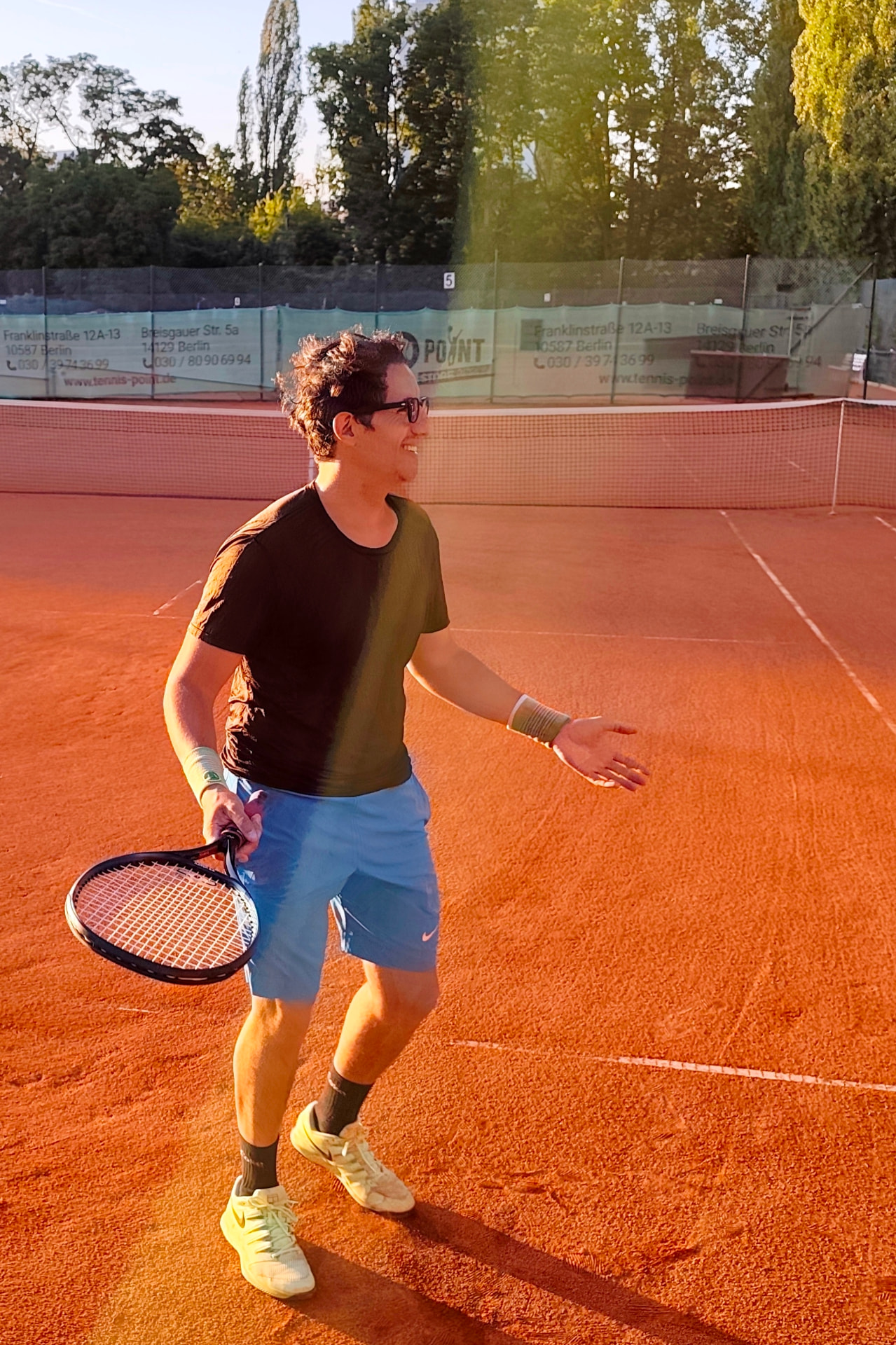 Youpi, tennis coach in Berlin, smiling on a clay court